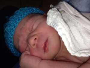 Newborn baby sleeping on side with blue woolen cap