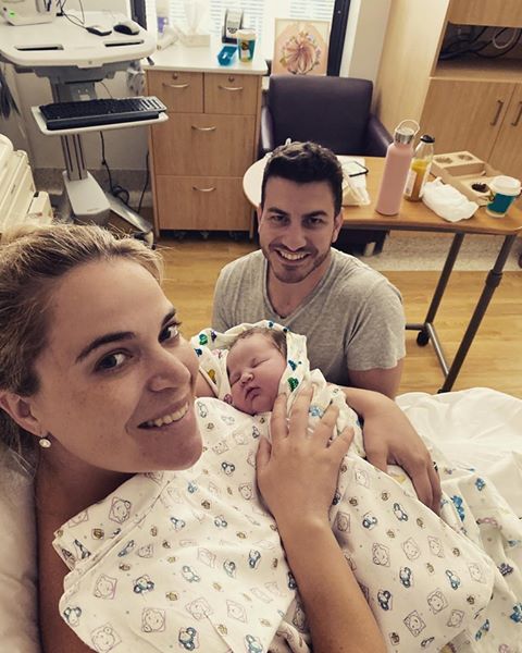 Mum in hospital holding baby with partner by her bedside