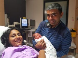 Mum in hospital bed with partner by her side holding newborn baby