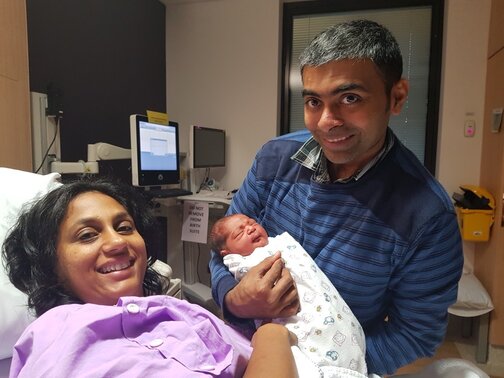 Mum in hospital bed with partner by her side holding newborn baby
