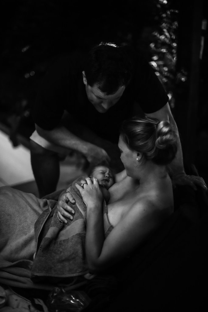 Mum holding baby in her arms with partner by her side