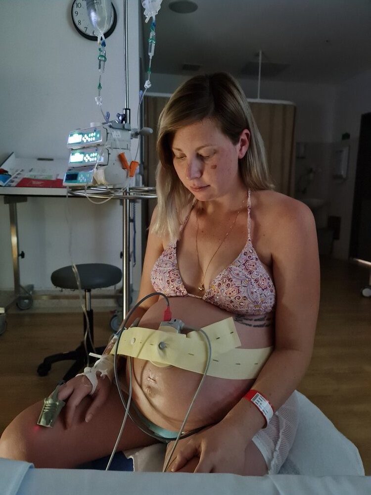 Pregnant mum labouring in hospital with CTG monitor around her belly in hospital