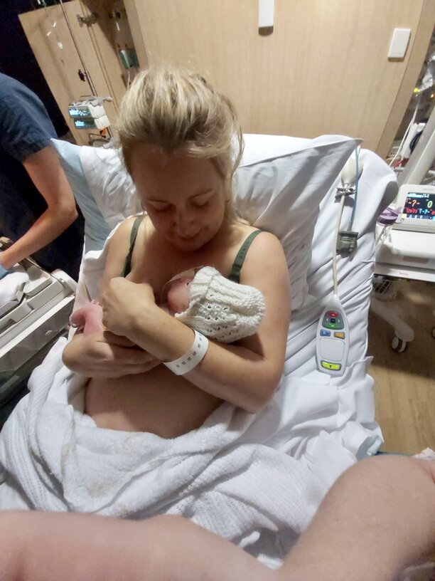 Mum cuddling baby while lying in hospital bed after birth