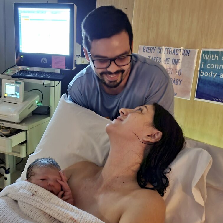 Mum looking lovingly at partner while cuddling baby skin to skin