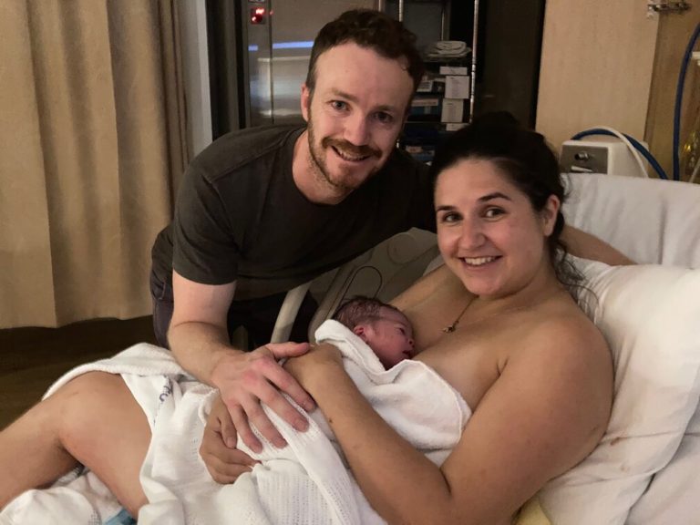 Mum holding baby on her chest skin to skin with partner beside her
