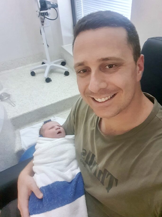 Dad holding his wrapped up newborn baby in his arms