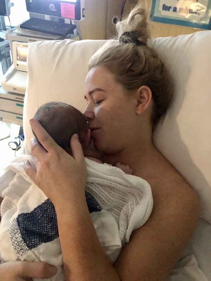 Mum cuddling newborn baby in hospital bed