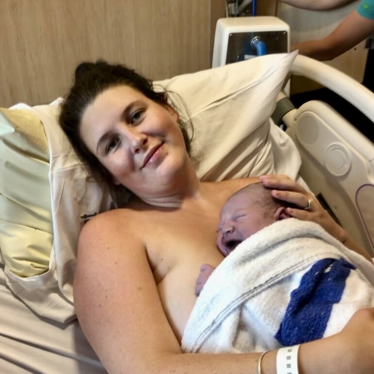 Mum lying on hospital bed with newborn baby on her chest skin to skin