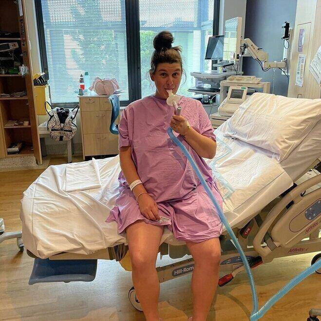 pregnant mum sitting on bed hospital bed holding gas and air