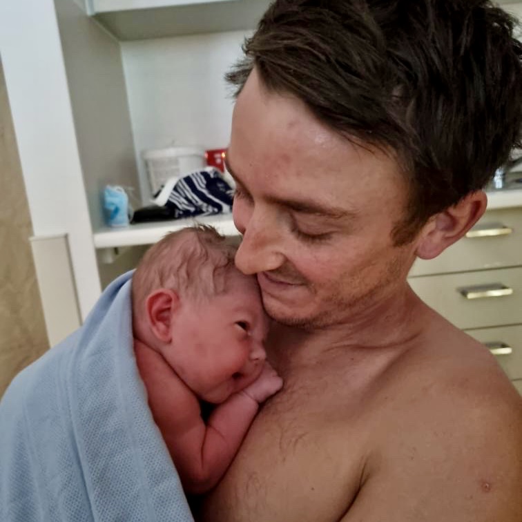 Dad cuddling newborn baby skin to skin
