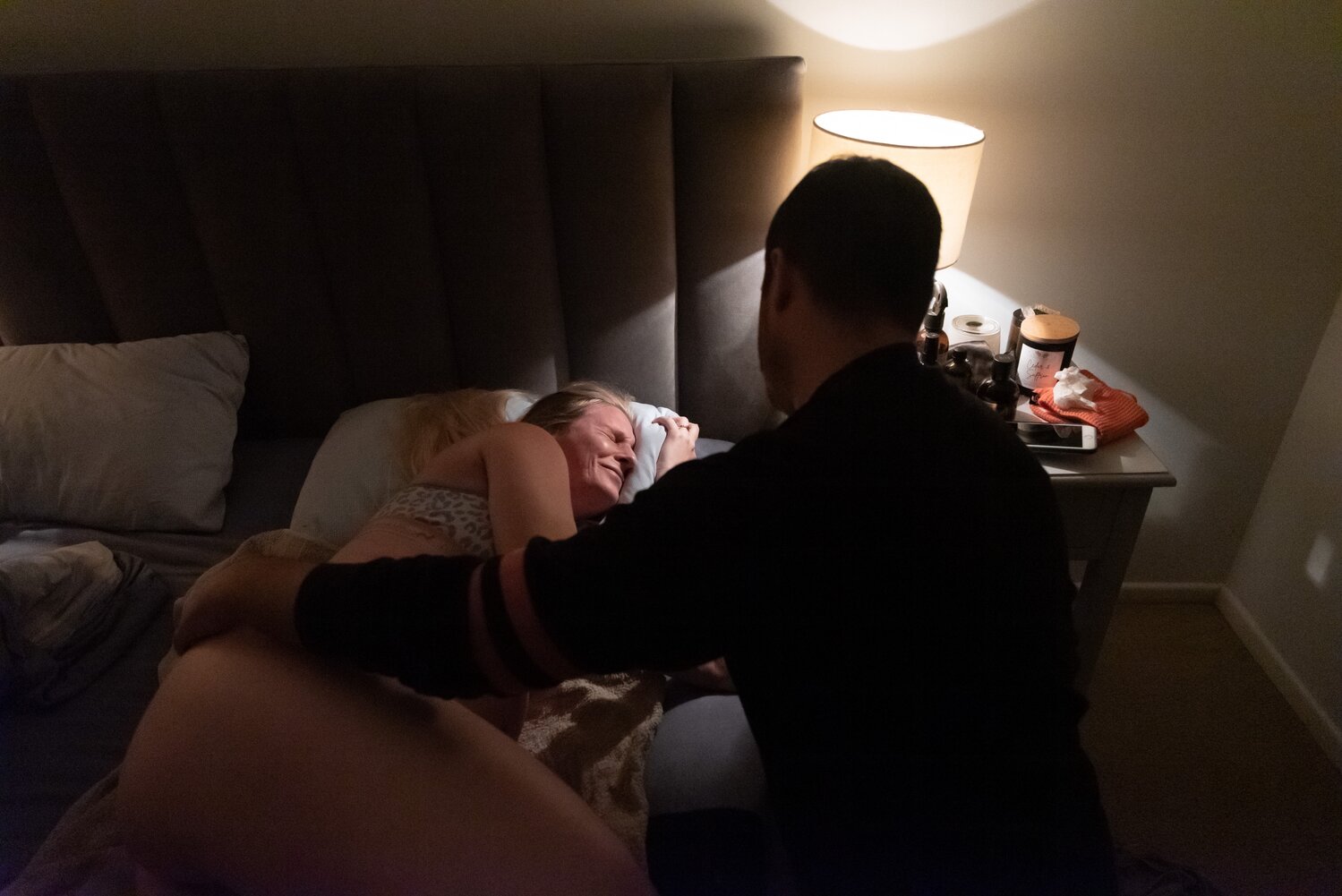 Pregnant mum in labour lying in bed with partner by her side