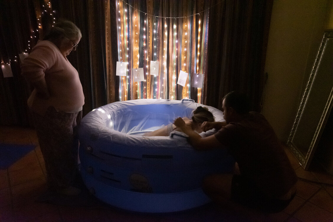 Pregnant mum in birth pool with fairy lights and dim lighting 