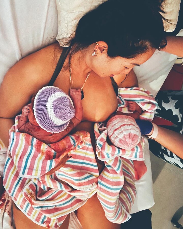 Twin baby girls on mother's chest breast feeding