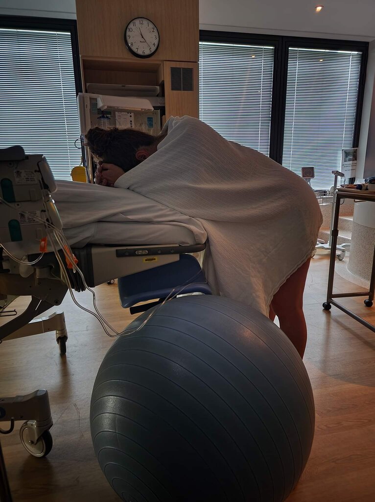 Pregnant mum in labour leaning over bed doing hypnobirthing breathing techniques