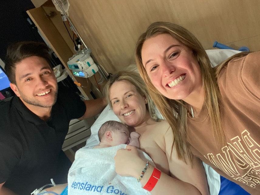 mum holding newborn baby on her chest with dad and their doula by her side