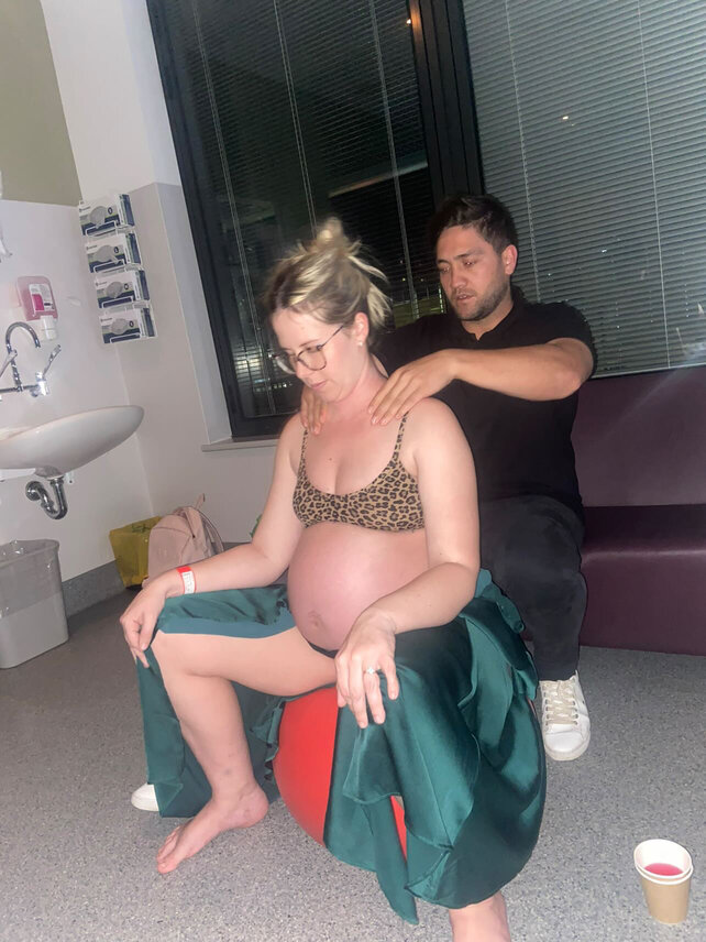 pregnant mum sitting on birth ball with partner doing hypnobirthing techniques