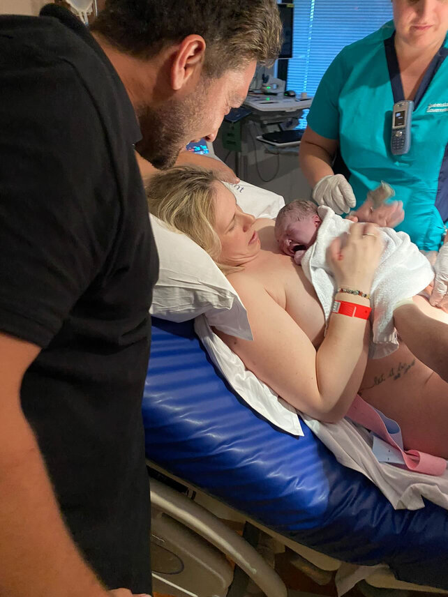 Mum with newborn baby on her chest skin to skin with partner by her side 