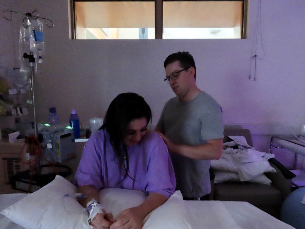 pregnant mum labouring in hospital with partner doing hypnobirthing techniques to calm