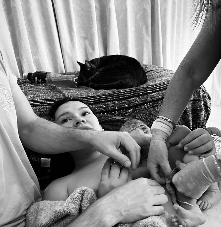 mum with baby on her chest skin to skin and umbilical cord being clamped