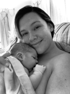 Mum cuddling newborn baby and smiling