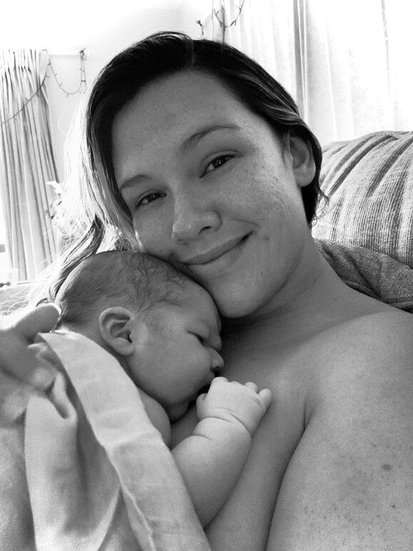 Mum cuddling newborn baby and smiling
