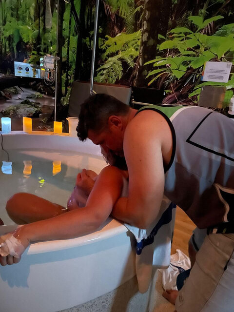 Mum labouring at the Birth Centre in birth pool with her partner holding her up and supporting