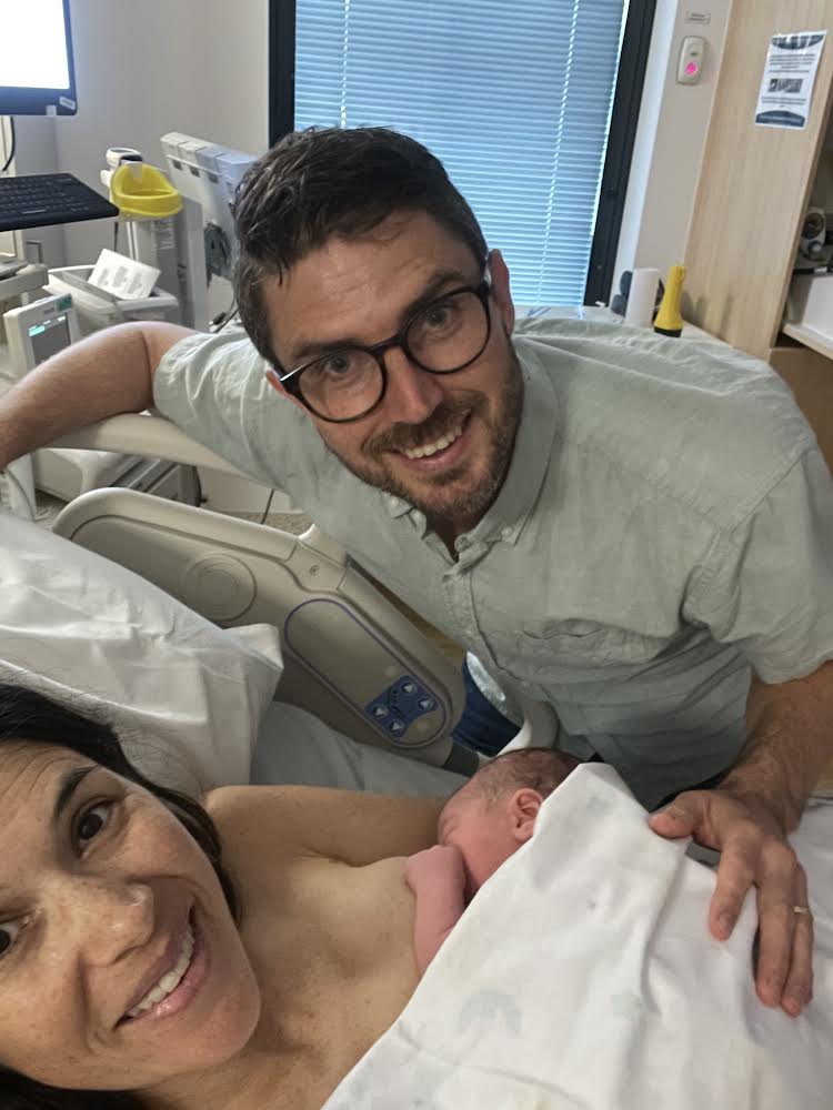 mum in hospital bed holding newborn baby with dad