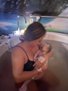 Mum in birth pool holding newborn baby boy