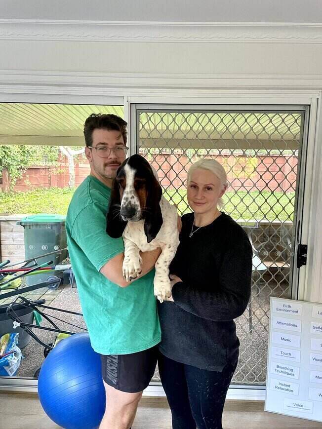 Pregnant couple holding dog after doing hypnobirthing private classes at home