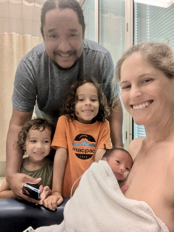 Mum just given birth with newborn baby with family  smiling