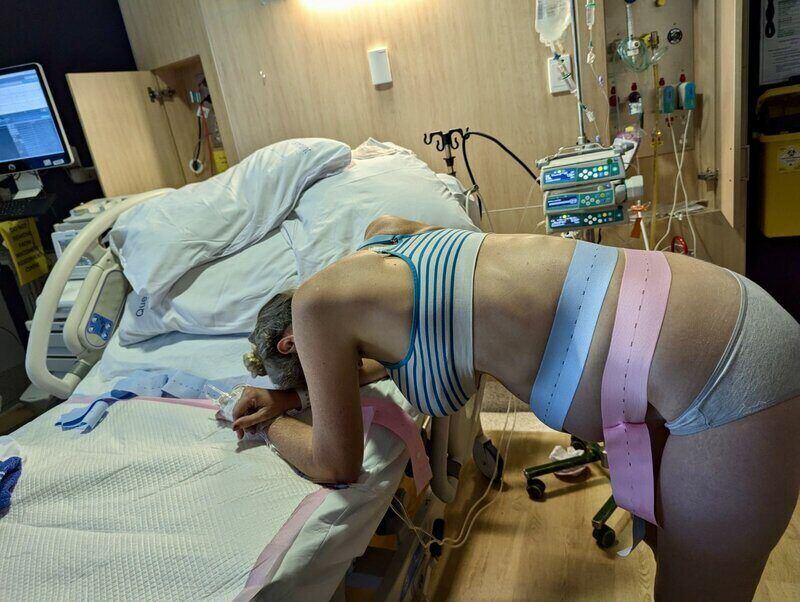 Woman in hospital in labour leaning on hospital bed