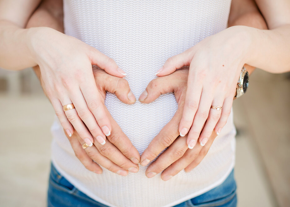 Pregnant Couple with hands on belly and doing heart sign