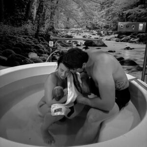 Mum and partner holding newborn baby in birth pool at birth centre