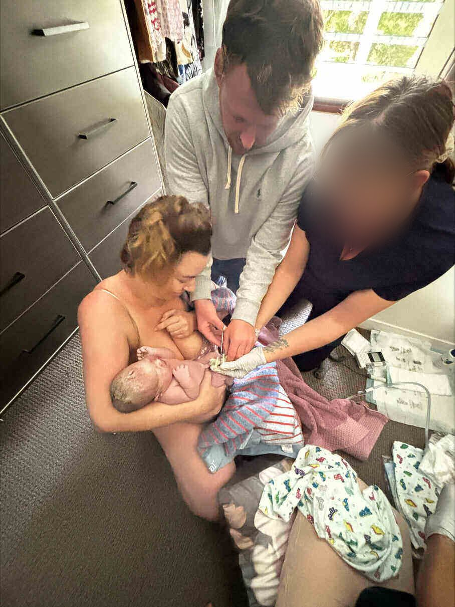 Joe cutting the cord while Brooke holds their newborn girl skin-to-skin after her positive home birth