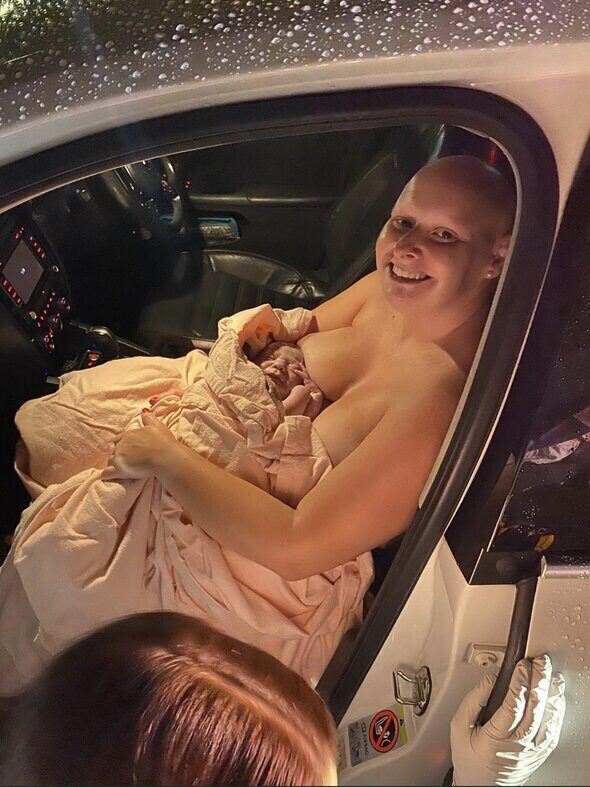 Smiling mum holding her newborn wrapped in a blanket in the front seat of the car after her fast hypnobirthing car birth
