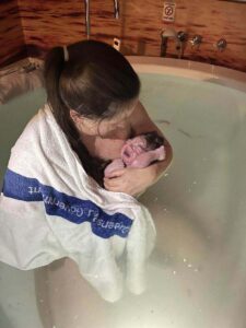 Mum holding her newborn in the birth pool after a calm hypnobirthing water birth
